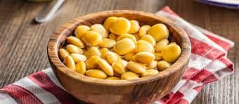 Yellow pickled lupini beans (tremoços) served in a small bowl, showing their characteristic oval shape and golden color