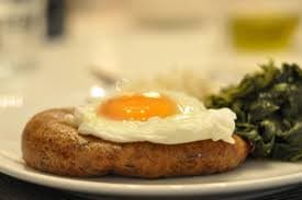 Golden-brown fried alheira sausages served alongside sunny-side up eggs with runny yolks on a white plate