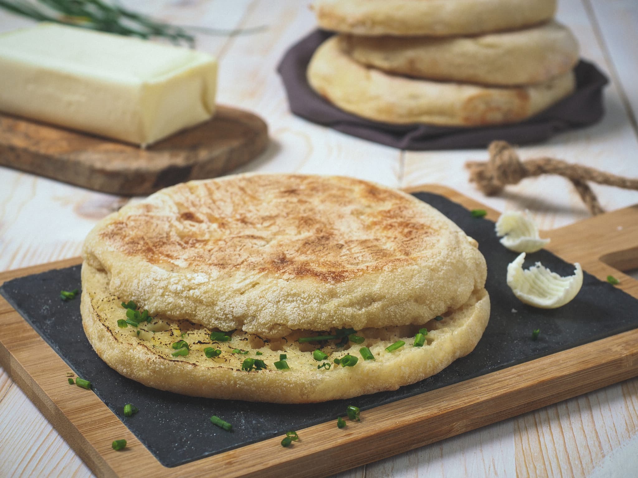 Round golden-brown flatbread split open and filled with melted garlic butter and fresh parsley, showing the soft, airy interior texture