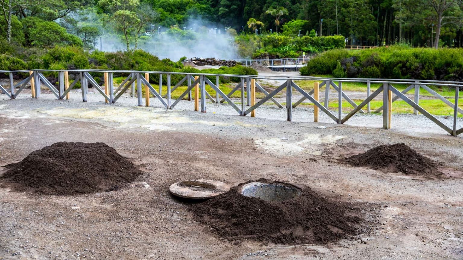 Steam rising from metal pots being lifted from volcanic soil holes in Furnas, Azores, with the traditional Cozido das Furnas stew being prepared using natural geothermal heat