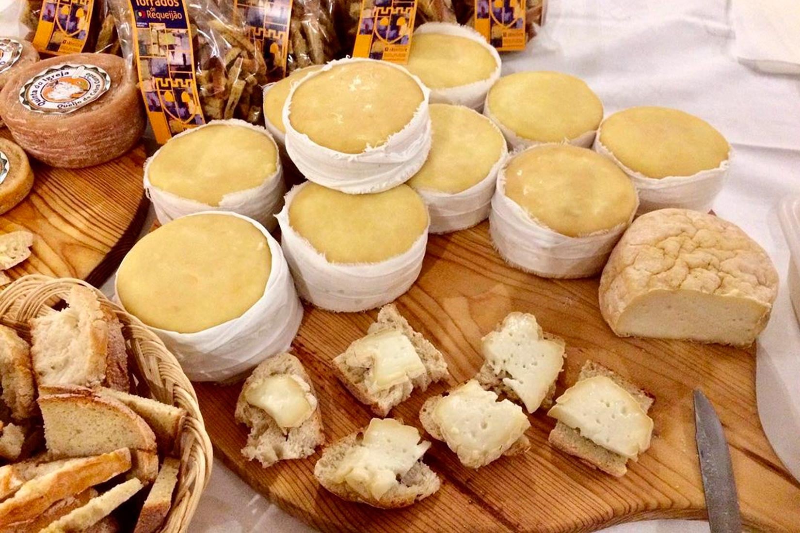 Wheels of golden Serra da Estrela cheese aging on wooden planks in a traditional Portuguese cheese cave, with muslin bandages visible around the cheese wheels