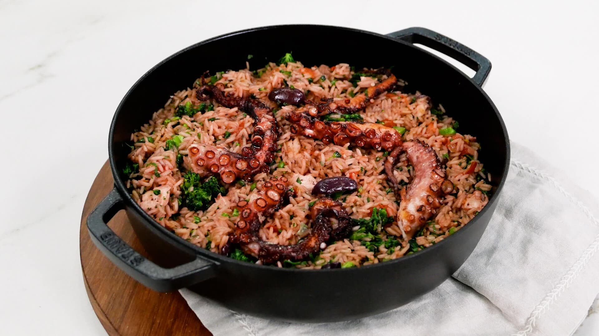 A rustic bowl of Portuguese arroz de polvo with tender octopus pieces nestled in creamy rice, garnished with fresh herbs, photographed in a traditional Portuguese kitchen setting
